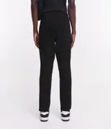 Pantalón de vestir marrón, de corte skinny, con bolsillos laterales y traseros. Se ajusta a la cintura con cinturón de cuero marrón.
