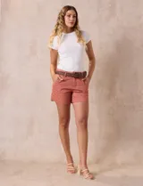 Short de jean azul oscuro con pretina con pasadores, botón y cierre. Delantera con bolsillos. Botón en bolsillos traseros. Incluye cinturón trenzado marrón con hebilla redonda dorada.