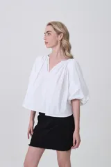 Blusa blanca de algodón con escote en V y frunces en el cuello, mangas abullonadas cortas y calce holgado.