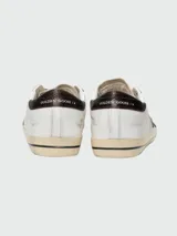 Championes Golden Goose modelo Super-Star, de cuero blanco con estrella verde y talón con estampado animal print.