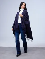 Ruana de tejido suave color negro con terminación en flecos, diseñada para un look cómodo y elegante.