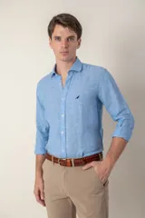 Camisa celeste de lino con cuello clásico y manga larga. Presenta un pequeño logo bordado en el pecho.