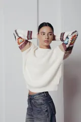 Sweater de punto color crema con cuello redondo y mangas largas con diseño geométrico en tonos beige, rojo, azul y blanco.