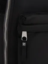 Mochila negra de nailon con diseño monocromático y paneles texturizados. Presenta un parche tonal con el logo de Tommy Jeans en la parte delantera y un bolsillo exterior con cremallera.