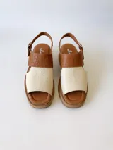 Sandalia de cuero color camel y crudo, con tira ancha sobre los dedos, tira al tobillo con hebilla y suela track.