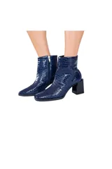 Botines de cuero vacuno azul marino con efecto croco brillante. Tienen caña media, cierre lateral y tacón bloque negro brillante de aproximadamente 7 cm.