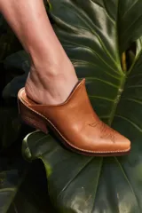 Mules de cuero color crema con punta fina y bordado estilo western en el empeine.