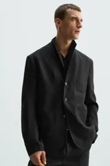 Blazer relaxed fit de lino color negro, con cuello solapa, manga larga, bolsillos frontales de plastrón y cierre frontal con botones. Interior sin forro.