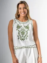 Musculosa blanca con bordado floral verde en el frente, cuello redondo y corte holgado.