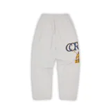 Pantalón de jogging gris con estampado del logo de Corteiz Lion en azul y amarillo en la pierna izquierda.