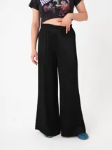 Pantalón ancho de silueta loose en color negro, confeccionado en tejido arrugado que aporta elegancia.