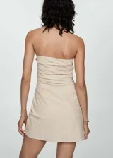Minivestido strapless color beige con textura de rayas diagonales, diseño drapeado y cierre lateral invisible.
