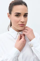 Camisa blanca de manga larga con puños fruncidos y cuello abotonado, corte holgado.