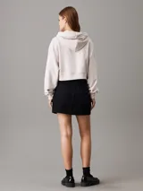 Buzo con capucha Calvin Klein color crema, de corte boxy y largo cropped. Presenta logo pequeño bordado en el pecho, cordones ajustables en la capucha y puños y bajo acanalados.