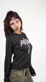 Remera corta negra de poliéster y elastano, con estampado de cruz rosa y alas blancas.