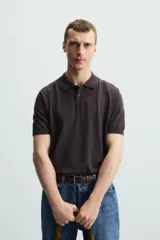 Polo negro de punto tejido en hilatura con algodón y lyocell, corte regular fit, cuello solapa con cierre frontal de botonadura, manga corta y acabados en rib.