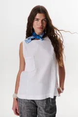 Top sin mangas color terracota con cuello redondo y bolsillo frontal. Presenta costuras a contratono en blanco que definen los bordes y el bolsillo.