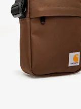 Bandolera Carhartt Jake de lona de poliéster reciclado repelente al agua, color negro, con compartimento principal con cremallera, bolsillo frontal y bolsillo interior de malla.