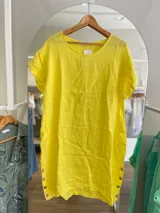 Vestido amarillo de lino con cuello redondo y mangas cortas con dobladillo. Tiene botones de madera en los laterales.