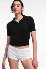 Top de punto color negro, con cuello polo, mangas cortas y diseño ajustado.