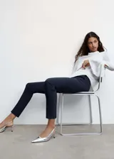 Pantalón negro de diseño crop, corte skinny y tiro medio. Cuenta con trabillas, dos bolsillos laterales, dos bolsillos de ribete en la parte posterior, cierre de cremallera y botón, y forro interior.