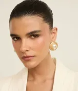 Caravanas de botón con diseño redondo y acabado en baño de oro batido, con una perla central de gran tamaño. Están confeccionadas en metal reciclado.