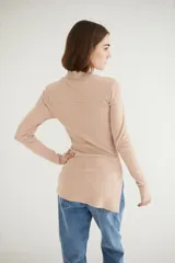 Remera de lycra color beige con cierre en el pecho y diseño de mangas largas y corte asimétrico.