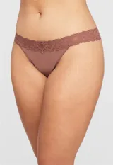 Panty colaless color beige de lycra con detalle de encaje floral en la cintura y pequeño dije de strass en el centro.