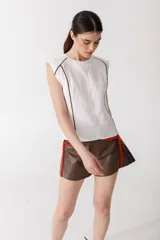 Blusa color ladrillo de lino 100% con cuello redondo y sin mangas. Presenta vivos y pespuntes a contratono en color marrón.