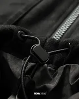 Campera bomber negra de gamuza sintética con cierre frontal, cuello alto, dos bolsillos superiores con solapa, puños y cintura ajustables.