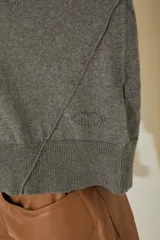 Sweater negro oversize de tejido de punto, con cuello alto y detalle de costuras a la vista.