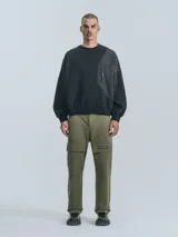 Buzo negro de cuello redondo, corte oversize y largo crop. Confeccionado en frisa gamuzada de algodón con recortes de microfibra y bolsillo delantero con cierre a presión.