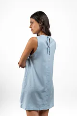 Vestido corto celeste de lino, sin mangas y con lazo en la espalda.