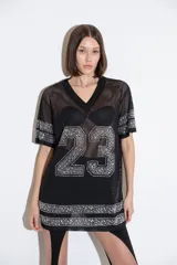 Camiseta negra de malla con cuello en V, mangas cortas y apliques de strass plateados formando el número 23 en el frente y detalles en las mangas y el ruedo.
