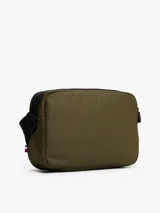 Bandolera Tommy Hilfiger color verde militar con detalles en negro y correa ajustable con la bandera de la marca. Incluye logo metálico en el frente y cierre de cremallera.