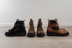 Botas de cuero color marrón oscuro, estilo Chelsea, con elástico lateral negro y suela track negra. Incluye correa de cuero desmontable con hebilla.