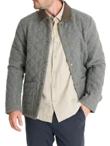 Chaqueta acolchada gris con patrón de rombos, cuello de pana marrón, cierre con broches metálicos, bolsillos frontales y bolsillo interno.