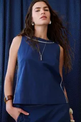 Top sin mangas color rosa pálido, con cuello redondo y vivos en color marrón oscuro en el cuello y a lo largo de las costuras laterales.