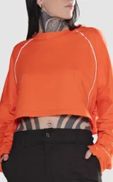 Remera corta naranja de manga larga con ribete blanco en las mangas.