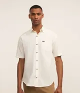 Camisa de hombre de corte relajado, color crudo, con cuello inglés, mangas cortas, abotonado delantero, bolsillo en el pecho y etiqueta de la marca.