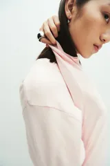 Buzo corto de punto fino color rosa claro, con cuello redondo y mangas largas.
