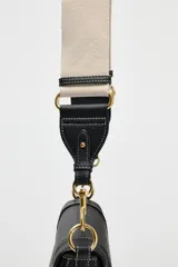 Bolso de hombro ovalado negro con asa de doble tira redonda con detalles metalizados dorados. Cierre imantado y asa de bandolera extraíble con tejido a contraste. Bolso interior con cierre mediante cremallera metálica.