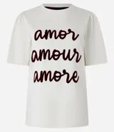 Remera color crema de algodón, corte slim, con cuello redondo y mangas cortas. Estampa frontal con las palabras 'amor', 'amour' y 'amore' en color borgoña.