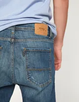 Pantalón de jean azul con roturas en las rodillas, corte slim fit.