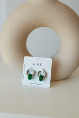 Aros de acero quirúrgico hipoalergénico con forma de argolla plateada y dije circular colgante de piedra natural color azul.