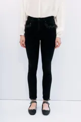 Jean slim negro de tiro medio-alto, calce al cuerpo y pierna semi-recta. Detalle de hotfix en bolsillos.