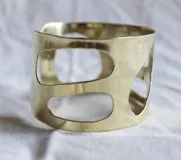 Brazalete de bronce con diseño orgánico y cortes irregulares, estilo contemporáneo.