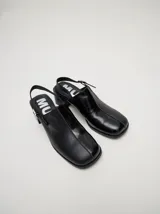 Mocasines color beige con taco bloque de madera color negro y correa trasera ajustable.