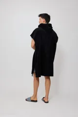 Poncho con capucha confeccionado en tejido de toalla de algodón, color negro, con el logo de la marca Rusty bordado en blanco en el frente.