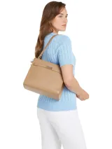 Cartera de hombro color beige con correa ajustable, cierre de solapa, dos compartimentos principales, un compartimento con cremallera, un bolsillo interior con cremallera y el monograma TH en la parte delantera.